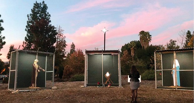 An individual reads a plaque in front of a life-size Nativity scene Dec. 11 displaying Jesus, Mary and Joseph as refugees in separate cages at Claremont United Methodist Church, in Claremont, Calif. The Nativity protests family separation at the border and has received widespread attention.