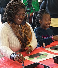 Tiya Shaw, left, works with her 7-year-old daughter, Shawn, on a harvest craft project in the festival’s area for youths.