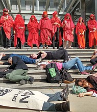 Members of Extinction Rebellion Richmond stage a silent die-in on the steps of City Hall in October to call attention to the need to act to abate climate change. Looking on are members who call themselves the “Red Rebel Brigade.”