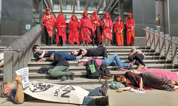 Members of Extinction Rebellion Richmond stage a silent die-in on the steps of City Hall in October to call attention to the need to act to abate climate change. Looking on are members who call themselves the “Red Rebel Brigade.”