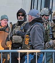 Men dressed in full military gear and carrying firearms stand in front of the state Supreme Court Building on 9th Street across from Capitol Square.