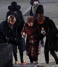 Holocaust survivor Bat-Sheva Dagan, center, is escorted as she places a candle in memory of those who died at the Nazi death camp in Auschwitz in Oswiecim, Poland. She returned to the camp this week for the commemoration of the 75th anniversary of the Soviet army’s liberation of the camp.