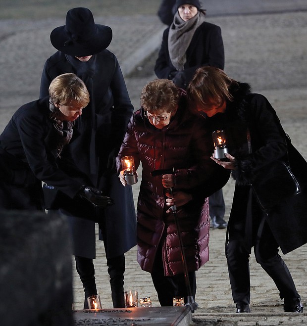 Holocaust survivor Bat-Sheva Dagan, center, is escorted as she places a candle in memory of those who died at the Nazi death camp in Auschwitz in Oswiecim, Poland. She returned to the camp this week for the commemoration of the 75th anniversary of the Soviet army’s liberation of the camp.