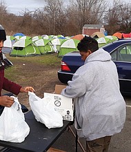 Svondai N. Brown, left, assists Rhonda L. Sneed in laying out supplies for residents of “Camp Cathy,” a homeless tent city on Oliver Hill Way. Ms. Sneed, founder and leader of blessing Warriors RVA, began setting up tents in September to improve living conditions and provide more order for those at the site in Shockoe Valley.