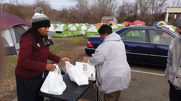 Svondai N. Brown, left, assists Rhonda L. Sneed in laying out supplies for residents of “Camp Cathy,” a homeless tent city on Oliver Hill Way. Ms. Sneed, founder and leader of blessing Warriors RVA, began setting up tents in September to improve living conditions and provide more order for those at the site in Shockoe Valley.