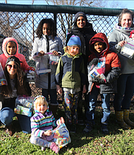 Ashley Smith-O’Meara, seated left, wants people to feel free to receive help without judgment or condition. She and other parents and children from the FERNNS Homeschool Co-op volunteering with the Walls of Love project in Richmond show off bags packed with personal items that will be put on the fence at Abner Clay Park in Jackson Ward. With her are, standing from left, her daughter, Sofia Ruffin, 9; Asfana Dawkins, 9; parent Umerah Mujahid; Sam Outland-Brock, 7; Jahid Dawkins, 8; parent Joy Outland-Brock holding her year-old daughter, Florence Outland-Brock; and seated front, Felicity Outland-Brock, 4.