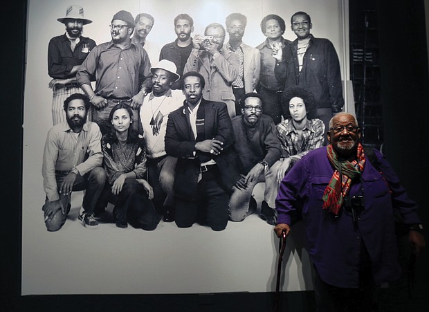 Shawn Walker, who was a member of the Kamoinge collective established by the late Henrico County native Louis Draper in New York City in 1963, stands in front of a historic photo of the group,  The exhibit will be on view through June 14 at the museum, 200 N. Arthur Ashe Blvd.