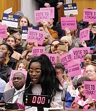 Naomi Isaac urges Richmond City Council to kill the $1.5 billion Coliseum replacement plan at Monday’s meeting. She was among a long line of people speaking on the proposal before council voted to scrap it. Behind her, supporters and opponents of the plan hold up signs reflecting their views.