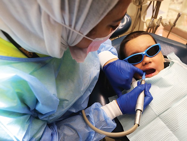 Bayron Rosales, 3, opens wide as Dr. Taibah AlBaker works on his mouth during VCu Dental Care Pediatric Dentistry’s annual day of free dental care last Friday at the Lyons Dental Building on 12th Street in Downtown. The effort was part of the American Dental Association’s annual “Give Kids A Smile” program begun in 2003 in which dentists, dental hygienists and dental assistants around the country volunteer their time and talents to provide free care to youngsters who otherwise would not have access to a dentist. In Richmond, pediatric dental specialists offered exams, cleanings, X-rays, fillings, extractions and minor restorations to youngsters without dental insurance. The national program kicks off National Children’s Dental Health Month.