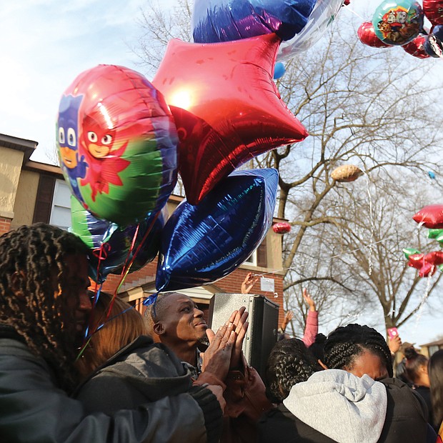 Dozens of people release colorful balloons in memory of 3-year-old Sharmar Hill Jr. during a prayer vigil last Saturday outside his family’s home in the 1700 block of Southlawn Avenue in Hillside Court. The youngster was shot and killed Feb. 1 as he played outside his home in the South Side public housing community.