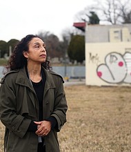 Lenora C. McQueen stands in the forgotten Grave Yard for Free People of Colour and For Slaves during a visit to Richmond. Behind her is the vacant, graffiti-marked mechanic’s shop at 1305 N. 5th St. In the background is the Hebrew Cemetery and the former white Richmond Alms House that now holds apartments for seniors.