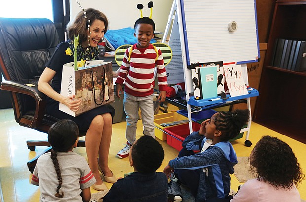 Virginia First Lady Pam Northam, laden with a bag full of show-and-tell items, settles in to read “When Spring Comes” to kindergartners at Overby-Sheppard Elementary School in Highland Park on Monday during the annual Read Across America Day. She is helped by Jahmir Johnson, who dons bumble bee wings and antennae to illustrate signs of the coming spring.