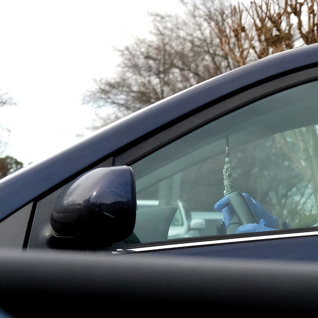 A motorist in Western Henrico wears a protective mask and gloves on Saturday.