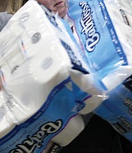 A customer stocks up on toilet paper at Costco, while below, others wait their turn at the Costco Saturday.