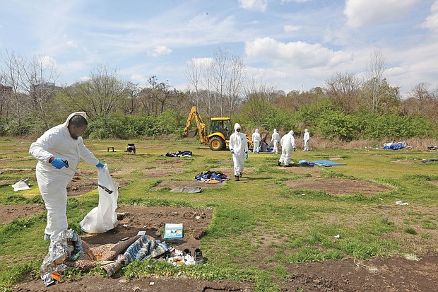 City employees dressed in hazmat suits Friday to clean up Cathy’s Camp on Oliver Hill Way. The property that belongs to Virginia Commonwealth University is to be fenced off to prevent a return of a homeless encampment.