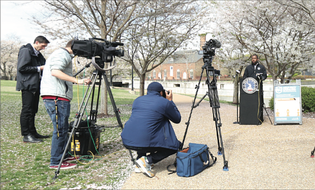 Reporters listen as Mayor Levar M. Stoney warns people on Tuesday that the city will shut down parks and other outdoor spaces if people don’t stop gathering in groups to play basketball and other games or continue to congregate at the river.