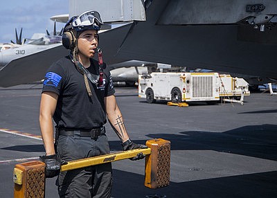 Airman Ramiro Fuentes, from Houston, follows an F/A-18 Super Hornet with a chock on the flight deck of the aircraft …