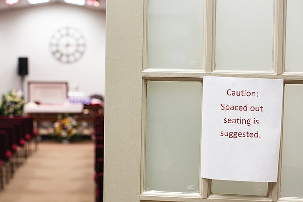 A sign on the door outside a viewing room reminds people to observe social distancing at Wilson & Associates’ Funeral Service in Henrico County.
