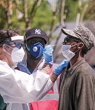 Lamire Balde is tested for the coronavirus by health care professionals at a Richmond Health District walk-up testing event Wednesday at the Southwood Apartments in South Side.