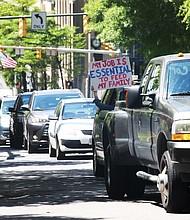 With horns honking and passengers waving signs, a line of vehicles carrying protesters descend on Downtown near the State Capitol on Wednesday demanding that Gov. Ralph S. Northam lift the restrictions put in place to curb the spread of the coronavirus and reopen Virginia’s economy.