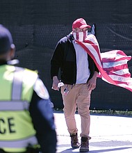 Police flank a protester walking along Broad Street near 8th Street. Many of the protesters had flags and Trump signs.