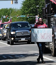 A woman walks with her sign as traffic on Broad Street comes to a standstill.