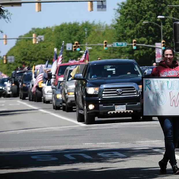 A woman walks with her sign as traffic on Broad Street comes to a standstill.
