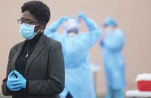 City Council President Cynthia I. Newbille listens intently during a news conference Tuesday before the opening of an outdoor COVID-19 testing site near Creighton Court in the East End. Behind her, medical personnel from the Richmond City Health District suit up to administer the tests.