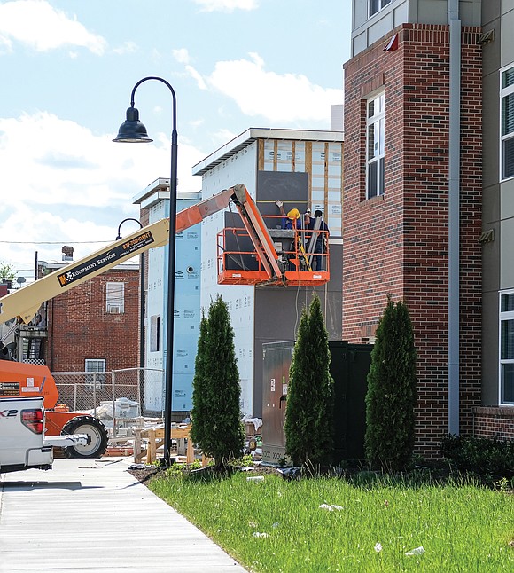 Workmen use a bucket truck to install panels at the 154-unit Jackson Ward Apartments in the block bounded by Duval, ...