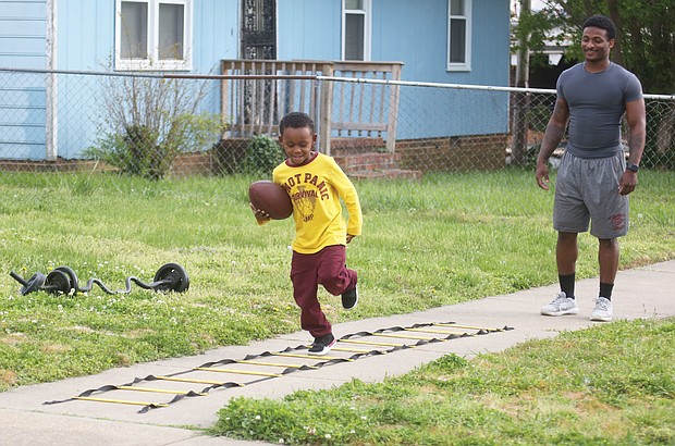 Virginia Union University running back, Andre Mack, 23, works out with his 5-year-old nephew, Ka’Reem Moore, on Tuesday in the 700 block of 30th Street in Church Hill. The youngster wants to play football like his uncle, a junior at VUU. The coaching and workout sessions also keep Mr. Mack in shape until the Panthers practice again in August, according to Mr. Mack. Until then, Mr. Mack is finishing his college courses online and having Zoom meetings with his teammates.
