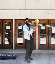 Isaiah “Prince Trombone” Robinson serenades passing motorists as fellow musician, Robert Johnson III, accompanies him on an electric drum outside The National in the 700 block of East Broad Street. The venue currently is closed because of the coronavirus. The two 23- year-old musicians began their impromptu concerts after they were laid off from their full-time gigs. Their goal: To deliver some upbeat sounds to counter the pandemic’s gloom and to possibly earn some spare change from the few pedestrians in Downtown. Other in Richmond musicians have been sharing their talents on their porches or in parks. One example is saxophonist James “Plunky” Branch, who regularly turns his porch into a solo concert platform for those within earshot in his West End neighborhood.