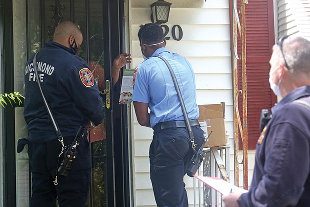 City firefighters Walter Davis, left, and Kevin Henderson, center, and fire Lt. Mark Chase deliver face masks, hand sanitizer and information to a resident on North 20th Street in Church Hill on Tuesday. The team from Fire Station 11 was taking part in the city’s effort to distribute thousands of protective items to people in the areas regarded as high risk for COVID-19.