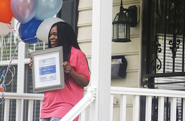 Rahmah T. Johnson proudly displays the plaque naming her Richmond’s Teacher of the Year last Friday. A counselor at Thomas Jefferson High School, Ms. Johnson found out about her selection when a delegation including Richmond Schools Superintendent Jason Kamras, Mayor Levar M. Stoney and other officials surprised her at her North Side home.