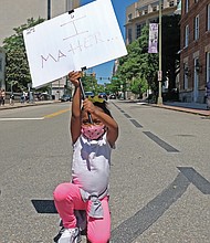 Nasiah Morris, 4, carries a sign with a powerful message during sunday’s peaceful grassroots march from Brown’s Island to the 17th street Market in shockoe Bottom. The youngster, kneeling at 9th and Grace streets across from the Capitol, attended the rally with her mother, Toya Morris, and 15-year-old brother, Tye.