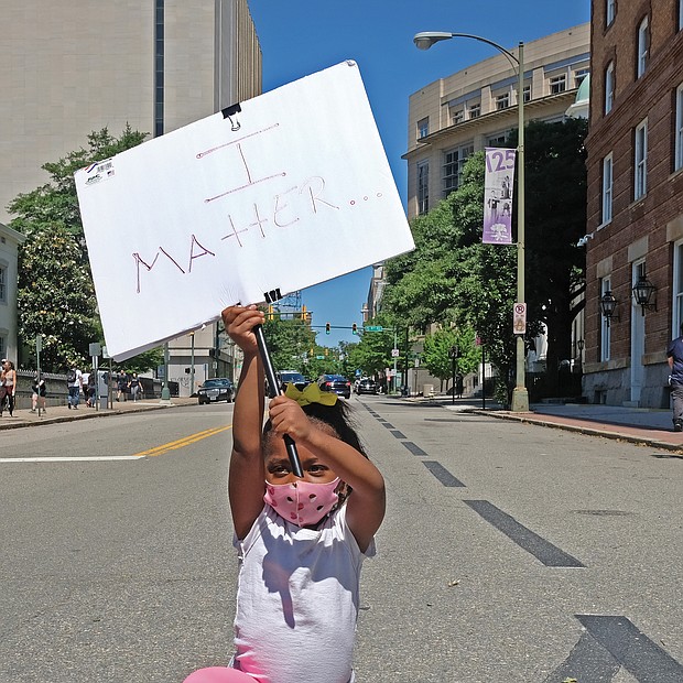 Nasiah Morris, 4, carries a sign with a powerful message during sunday’s peaceful grassroots march from Brown’s Island to the 17th street Market in shockoe Bottom. The youngster, kneeling at 9th and Grace streets across from the Capitol, attended the rally with her mother, Toya Morris, and 15-year-old brother, Tye.