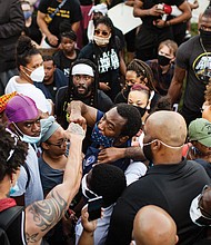 Mayor Stoney gives a fist-bump to a protester in the crowd Tuesday evening after walking with the throng from the state Capitol to the Lee statue on Monument Avenue.