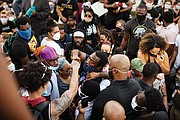 Mayor Stoney gives a fist-bump to a protester in the crowd Tuesday evening after walking with the throng from the state Capitol to the Lee statue on Monument Avenue.