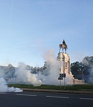 Tear gas clouds the air around the Monument Avenue statue of Confederate Gen. Robert E. Lee on Monday evening when Richmond Police scattered hundreds of peaceful protesters by releasing tear gas and shooting pepper spray about 30 minutes before the 8 p.m. curfew was to go into effect. The Confederate statues are headed for removal under plans announced Wednesday.