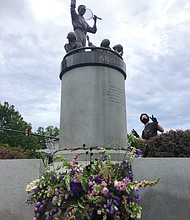 Volunteers for Vessel + Stem place flowers from Fourteen Acres Flower Farm around the statue of tennis star Arthur Ashe Jr. on Monument Avenue in late May.