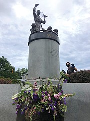 Volunteers for Vessel + Stem place flowers from Fourteen Acres Flower Farm around the statue of tennis star Arthur Ashe Jr. on Monument Avenue in late May.