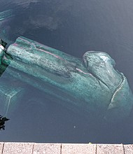 The statue of Christopher Columbus floats in Fountain Lake after it was knocked down Tuesday night following a protest where the statue stood for decades at Byrd Park.