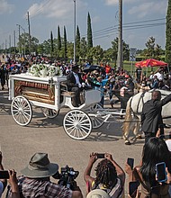 The coffin of George Floyd proceeds to his final resting place next to his mother inside Houston Memorial Gardens in Pearland, Texas, on Tuesday as throngs capture the picturesque farewell on their phones.