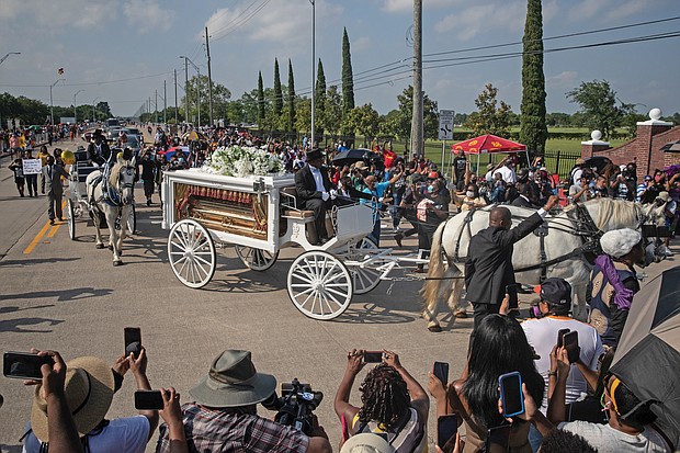 The coffin of George Floyd proceeds to his final resting place next to his mother inside Houston Memorial Gardens in Pearland, Texas, on Tuesday as throngs capture the picturesque farewell on their phones.