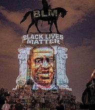 A Black Lives Matter tribute to the late George Floyd is projected onto the statue of Confederate Gen. Robert E. Lee on Saturday night by local artist Dustin Klein, a striking signal of change.