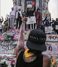 Protesters raise their fists in solidarity at the Robert E. Lee statue Saturday afternoon.