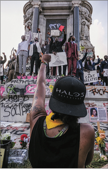 Protesters raise their fists in solidarity at the Robert E. Lee statue Saturday afternoon.