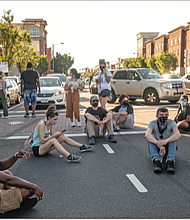 A band of demonstrators sit, stand and pray at the intersection of Belvidere and Broad streets on Sunday, temporarily blocking traffic at one of the most heavily traveled locations in the city.