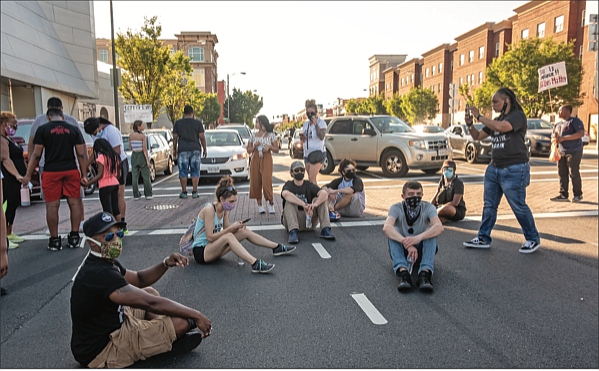 A band of demonstrators sit, stand and pray at the intersection of Belvidere and Broad streets on Sunday, temporarily blocking traffic at one of the most heavily traveled locations in the city.