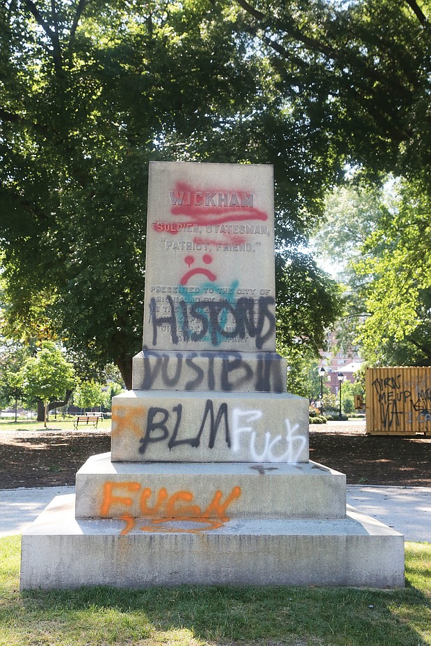 Above, the graffiti-tagged pedestal is all that remains where the statue of Confederate Gen. Williams Carter Wickham once stood in Monroe Park. Protesters pulled down the statue Saturday night. The Virginia National Guard reportedly now has it.