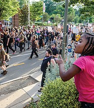 Marasia Robertson, 4, watches as hundreds of protesters march peacefully down Franklin Street last Friday, one in a succession of civil actions taken in Richmond since the death of George Floyd in Minnesota. The youngster was with family at a local restaurant when the demonstrators marched by.
